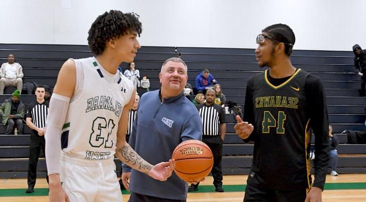 National Junior College Athletic Association (NJCAA), prepares to throw the jump ball. Players wait in anticipation.